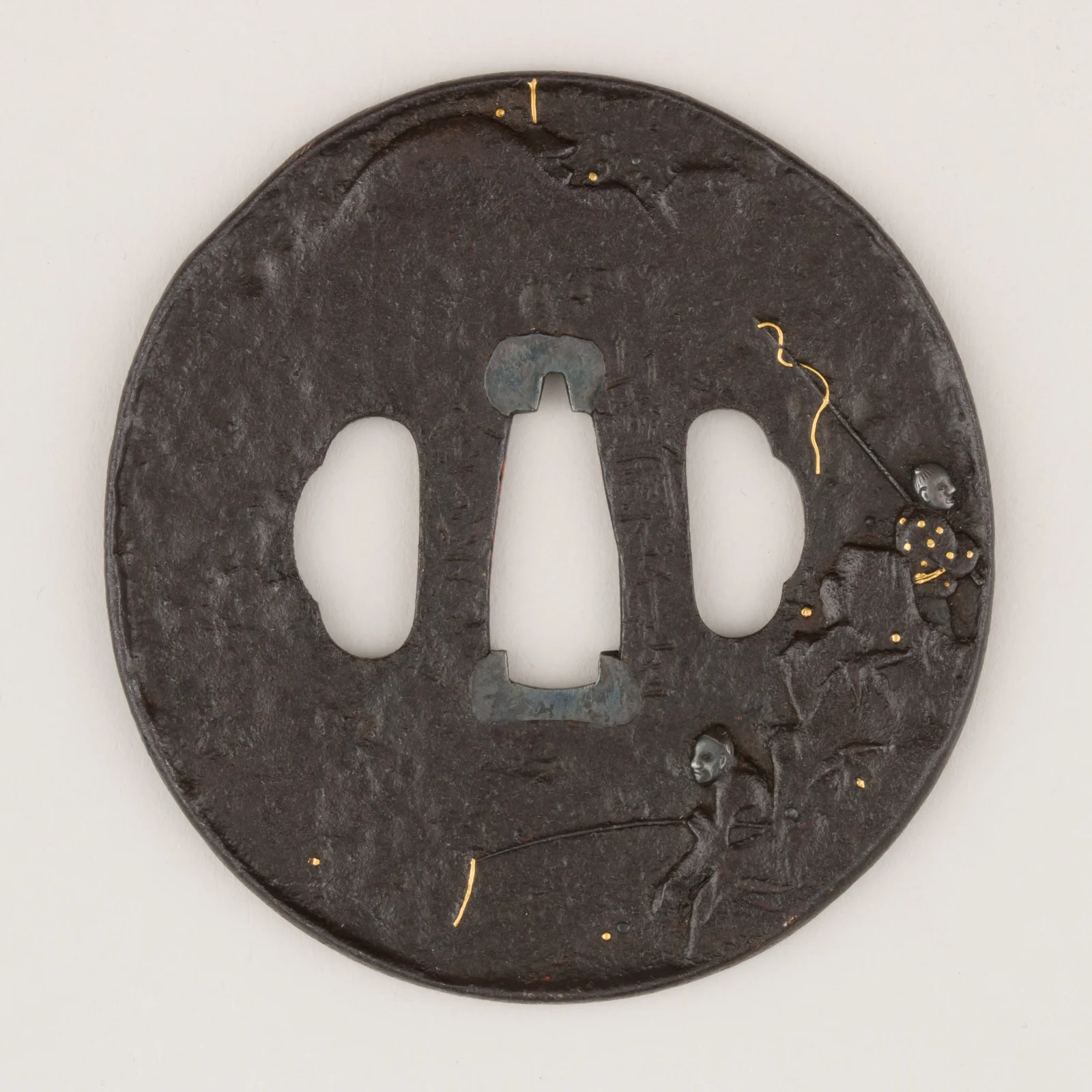 Guarda (tsuba) de hierro con incrustaciones doradas, con las dos aberturas laterales (hitsu-ana) para kozuka y kōgai.