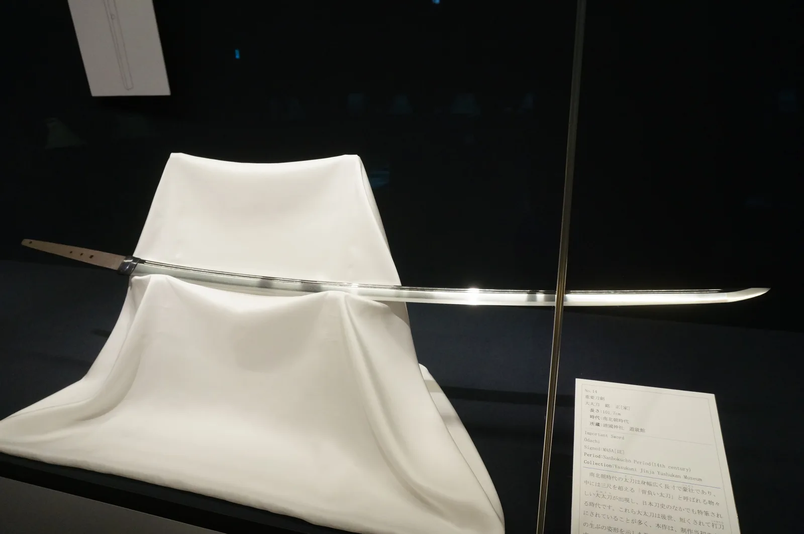 Ōdachi expuesto en vitrina, hoja larga y recta apoyada sobre un paño, junto a su cartela de museo.