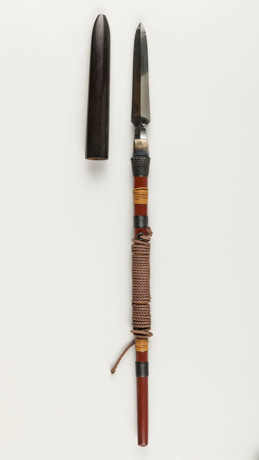 Punta de yari recta y de doble filo, con su funda de cuerno junto a ella y parte del asta envuelta en cordón.