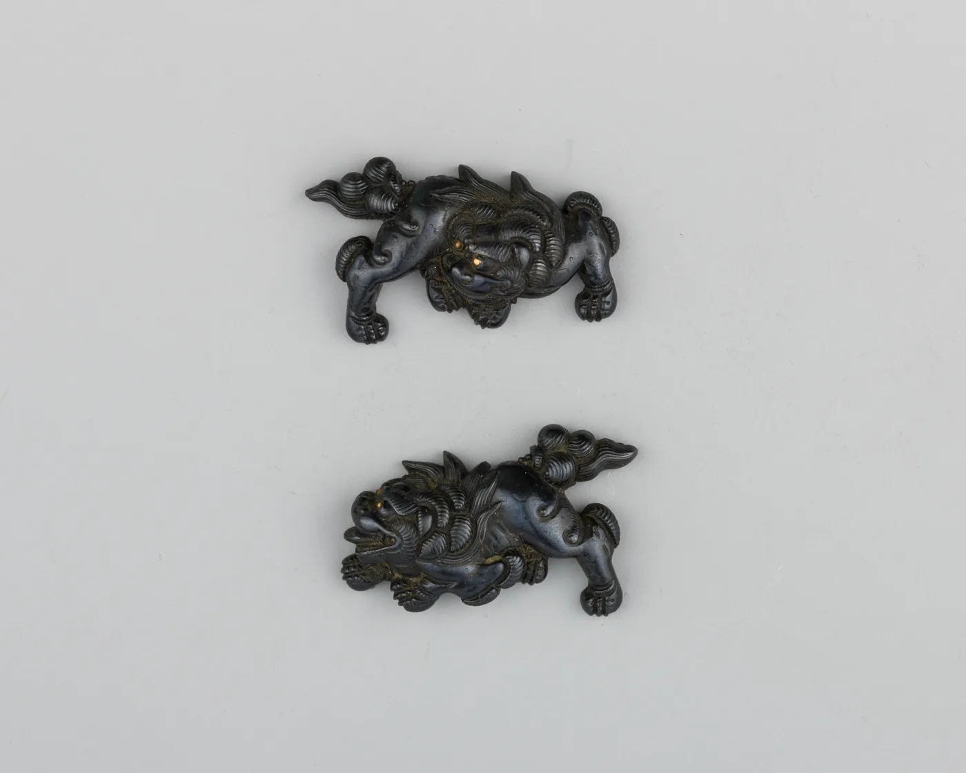 Par de menuki de bronce dorado con forma de shishi (león guardián), una figura enroscada bajo cada trenzado.