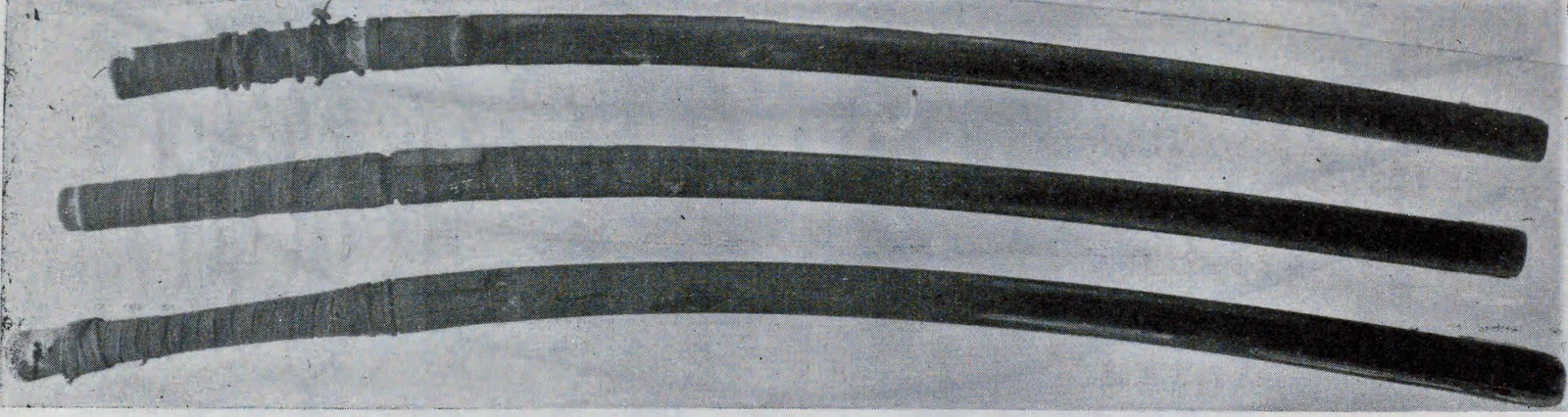 Tres monturas de uchigatana de laca negra lisa, fotografiadas una junto a otra.