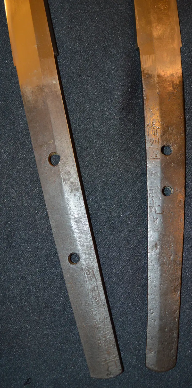 Dos espigas (nakago) de hojas antiguas kotō de la provincia de Bizen, una de un tachi y otra de una katana, fotografiadas juntas para comparar dónde queda grabada la firma (mei) y la posición de los orificios (mekugi-ana).